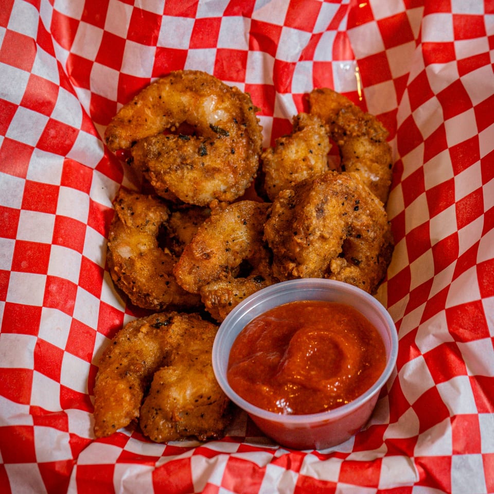 Chicks Chicken fried shrimp with dipping sauce in a red and white checkered basket.