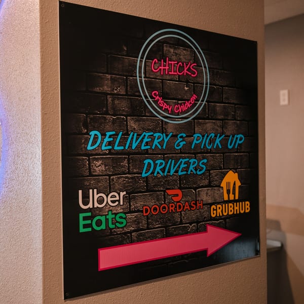 A Chicks Crispy Chicken sign for delivery and pick-up drivers, with logos for Uber Eats, DoorDash, and Grubhub.